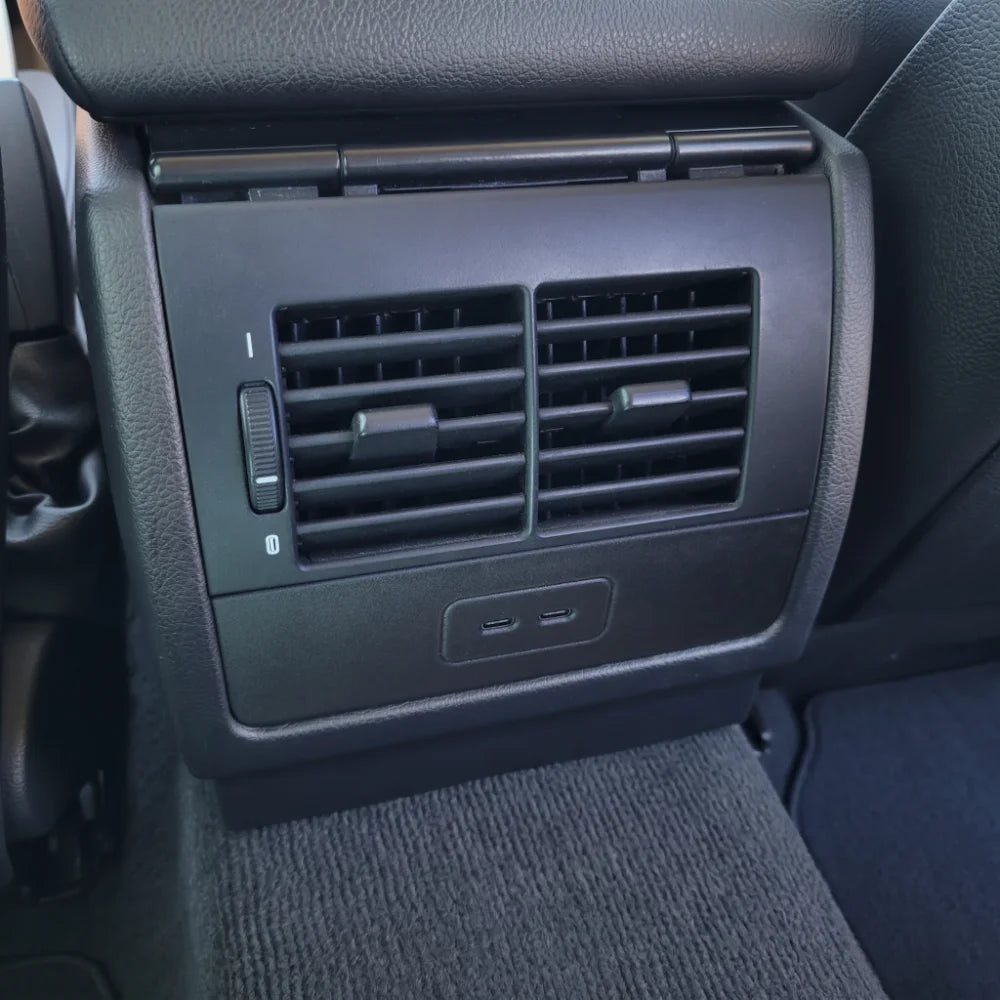 Close-up of a BMW E39 dual port 65 watt rear charging station in a black E39 interior
